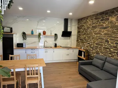 a kitchen and living room with a stone wall at Boutique Vila de Triacastela in Tríacastela