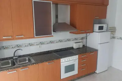 a kitchen with wooden cabinets and a white refrigerator at Apartamento céntrico in Foz
