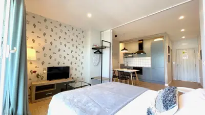 a bedroom with a bed and a tv and a kitchen at The Cliffs A Ribeira - Llas in Foz