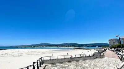 a beach with a fence and people on the sand at The Cliffs A Ribeira - Areoura in Foz