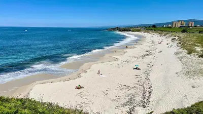 a group of people on a beach next to the ocean at The Cliffs A Ribeira - Areoura in Foz