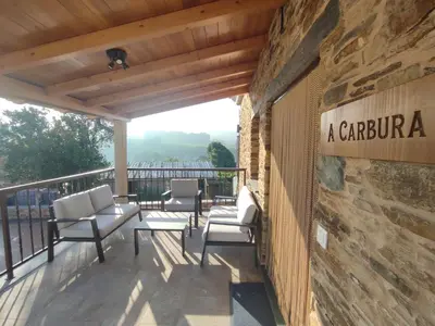a patio with chairs and a stone wall at Apartamentos Rurales Torre de la Alcandra - 3 llaves - Asturias in Vegadeo