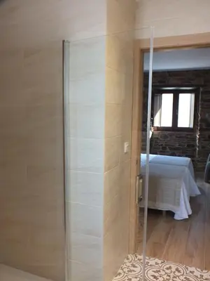 a glass shower in a room with a bed at Apartamentos Rurales Torre de la Alcandra - 3 llaves - Asturias in Vegadeo