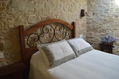 a bed in a room with a stone wall at Casa Labrega da Torre in Silleda