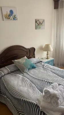 a bed with a wooden headboard and a table with a lamp at As pontes apartamento in Puentes de García Rodríguez