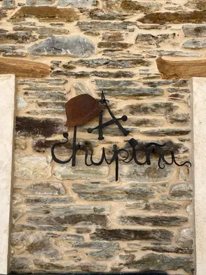 a metal sign on the side of a stone wall at A Chupiña in Balboa