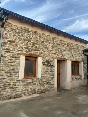 a stone building with two windows and a door at A Chupiña in Balboa