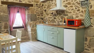 a kitchen with blue cabinets and a red microwave on a counter at Apartamentos Muralla Sacra in Sober