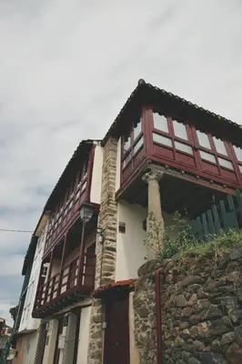 a building with wooden windows and a stone wall at Casa Trillo en centro de Monforte de Lemos in Monforte de Lemos