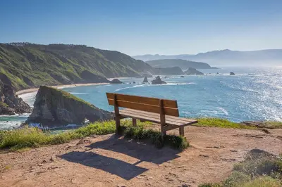 a wooden bench sitting on top of a beach at Pazo da Trave in Viveiro