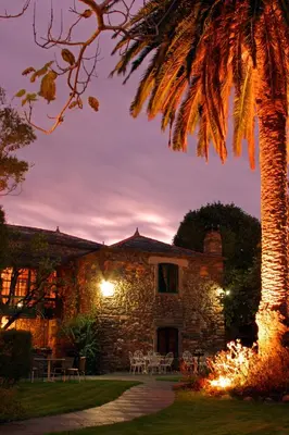 a stone building with tables and a palm tree at Pazo da Trave in Viveiro