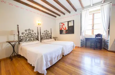 two beds in a white room with wooden floors at Pazo da Trave in Viveiro