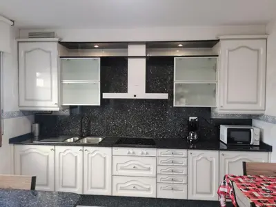 a kitchen with white cabinets and a sink and a microwave at Apartamento entero Frama Caldas in Caldas de Reis