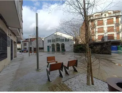 two benches on a city street with a building at Apartamento entero Frama Caldas in Caldas de Reis
