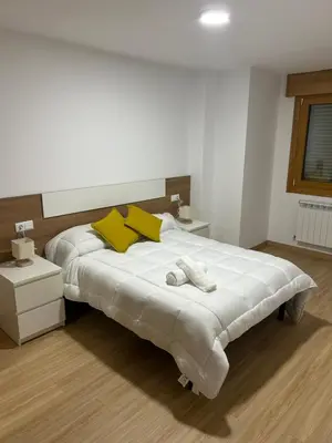a bedroom with a large white bed with yellow pillows at Piso de diseño in Verín