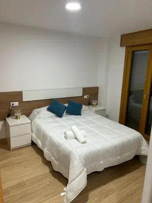 a bedroom with a large white bed with blue pillows at Piso de diseño in Verín