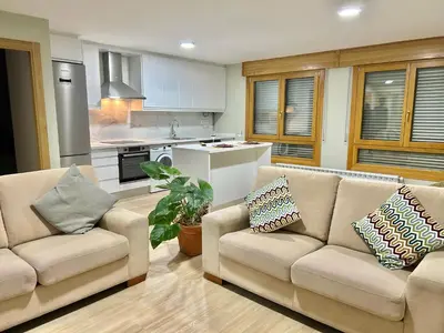 a living room with two couches and a kitchen at Piso de diseño in Verín