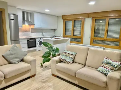a living room with two couches and a kitchen at Piso de diseño in Verín