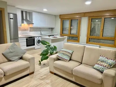 a living room with two couches and a kitchen at Piso de diseño in Verín