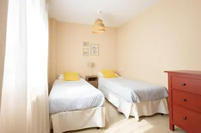 a bedroom with two beds with white sheets and yellow pillows at Casa Miño Golf in Miño