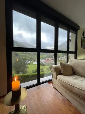 a living room with a candle on a table in front of a window at Los Diales in Cangas del Narcea
