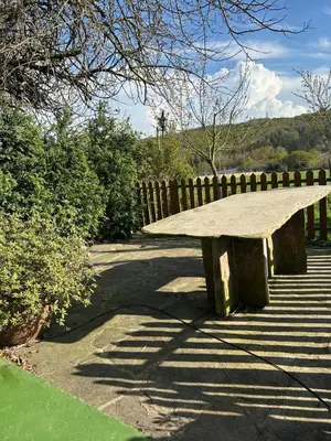 a wooden bench sitting on a sidewalk next to a fence at O Forno de Catuxa Cottage & Roman Wall in Lugo