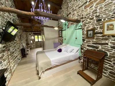 a bedroom with a bed and a stone wall at O Forno de Catuxa Cottage & Roman Wall in Lugo