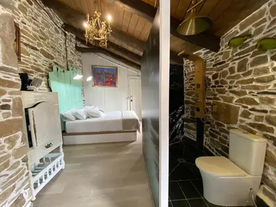 a room with a bed and a bathroom with a toilet at O Forno de Catuxa Cottage & Roman Wall in Lugo