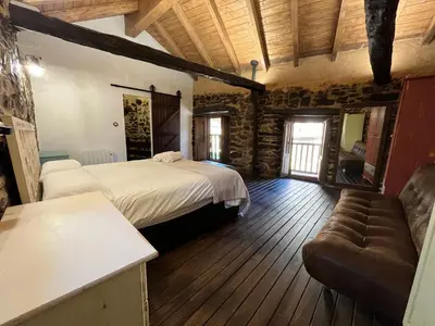 a bedroom with a bed and a couch in a room at La Casina de Gelo in Riego de Ambros
