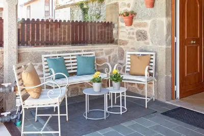 two chairs and a table with pillows on a patio at Casa Condomiña in Amés