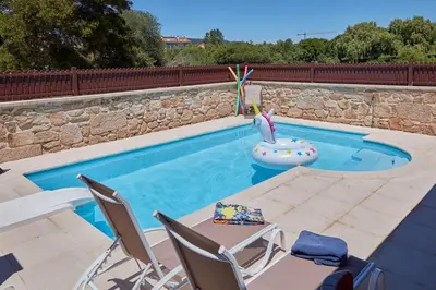 a swimming pool with two chairs and a swan float at Casa Condomiña in Amés