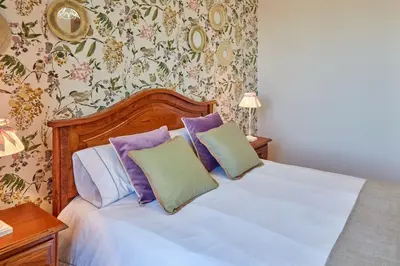 a bedroom with a white bed with purple and green pillows at Casa Condomiña in Amés