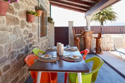a wooden table with colorful chairs on a patio at Casa Condomiña in Amés