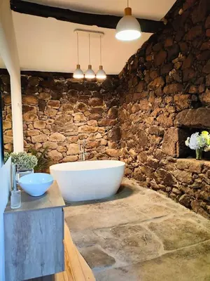 a bathroom with a tub and a stone wall at Casa Rural Xures Lobios in Ourense