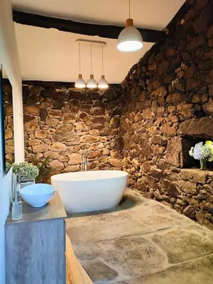 a bathroom with a tub and a stone wall at Casa Rural Xures Lobios in Ourense