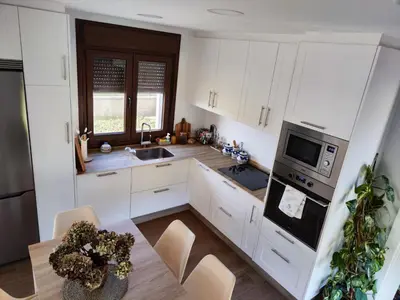 a kitchen with white cabinets and a wooden table at Villa Quelle in Sieiro