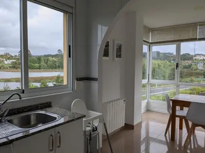 a kitchen with a sink and a table and windows at Playa de Miño in Miño