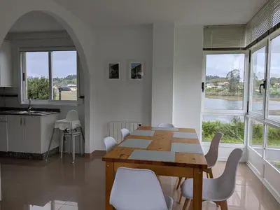 a dining room with a wooden table and white chairs at Playa de Miño in Miño
