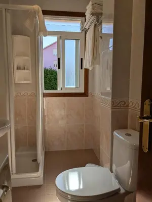 a bathroom with a white toilet and a window at Playa de Miño in Miño