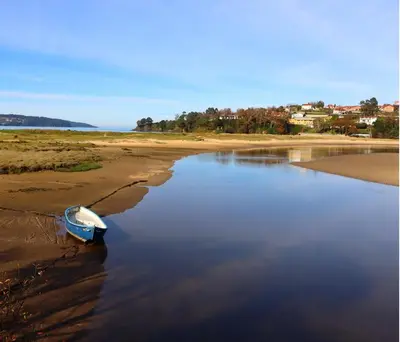 a small boat sitting on the shore of a beach at Playa de Miño in Miño