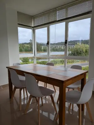 a wooden table and chairs in a room with windows at Playa de Miño in Miño
