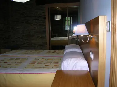 a bedroom with a bed with white sheets and a lamp at Finca O Bizarro in Trabada