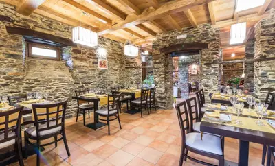a restaurant with tables and chairs in a stone wall at Finca O Bizarro in Trabada