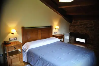 a bedroom with a large bed and a fireplace at Finca O Bizarro in Trabada