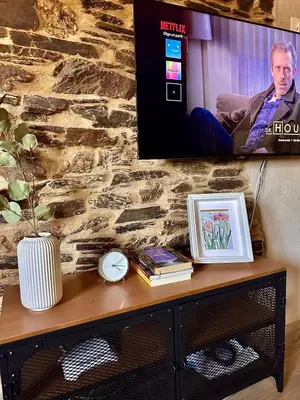 a tv on a stone wall with a table with a picture at CASA BORAL- Comfort exclusivo en plena naturaleza - Valle del Silencio in Manzanedo de Valdueza