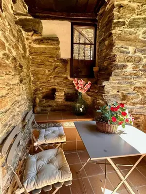 a table and chairs in a room with a stone wall at CASA BORAL- Comfort exclusivo en plena naturaleza - Valle del Silencio in Manzanedo de Valdueza