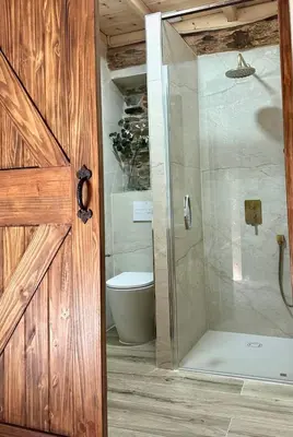 a bathroom with a shower with a toilet and a door at CASA BORAL- Comfort exclusivo en plena naturaleza - Valle del Silencio in Manzanedo de Valdueza