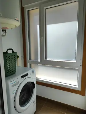 a laundry room with a washing machine and a window at Melide Suites By OL in Melide