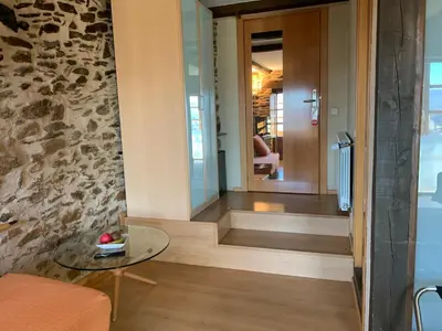 a hallway with a glass table and a stone wall at Posada Real La Carteria in Puebla de Sanabria
