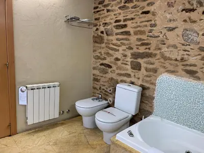 a bathroom with a white toilet and a bath tub at Posada Real La Carteria in Puebla de Sanabria